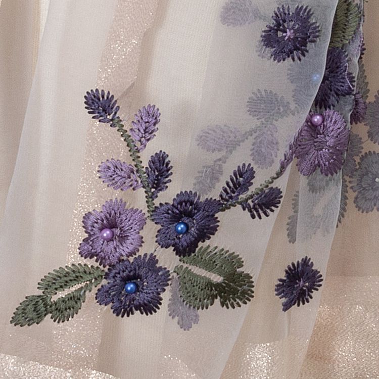Close view of purple floral embroidery and raised decorative details on sheer scarf fabric
